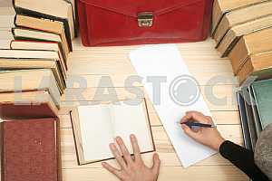 On a wooden table books, documents, calculator, red briefcase.