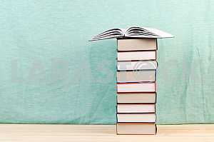 Открытая книга, стопка книг в твердом переплете на деревянном столе. Обратно в школу. Копирование пространства