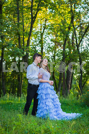 a love story couple, in love, together in the forrest park, girl in a beautiful violet dress, sunny evening, summer, thematic wedding shooting, frill dress