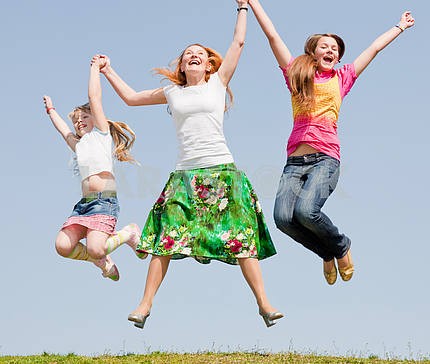 Happy Mother and two daughter jumping on green meadow