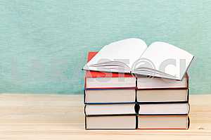 Открытая книга, стопка книг в твердом переплете на деревянном столе. Обратно в школу. Копирование пространства