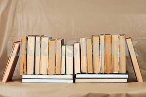 Old and used hardback books or text books on wooden table. Books and reading are essential for self improvement, gaining knowledge and success in our careers, business and personal lives. Copy space
