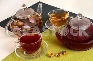 Flowering tea in clear glass teapot with teacups