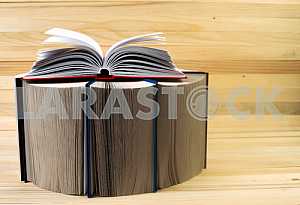 Открытая книга, стопка книг в твердом переплете на деревянном столе. Обратно в школу. Копирование пространства