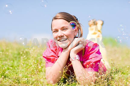 Pretty smiling girl relaxing on green meadow full of flowers. So