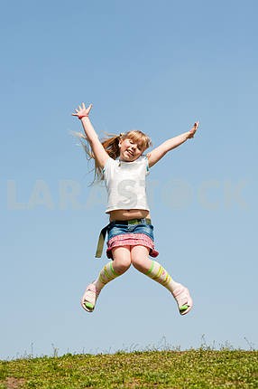 Маленькая девочка прыгает против красивых неба
